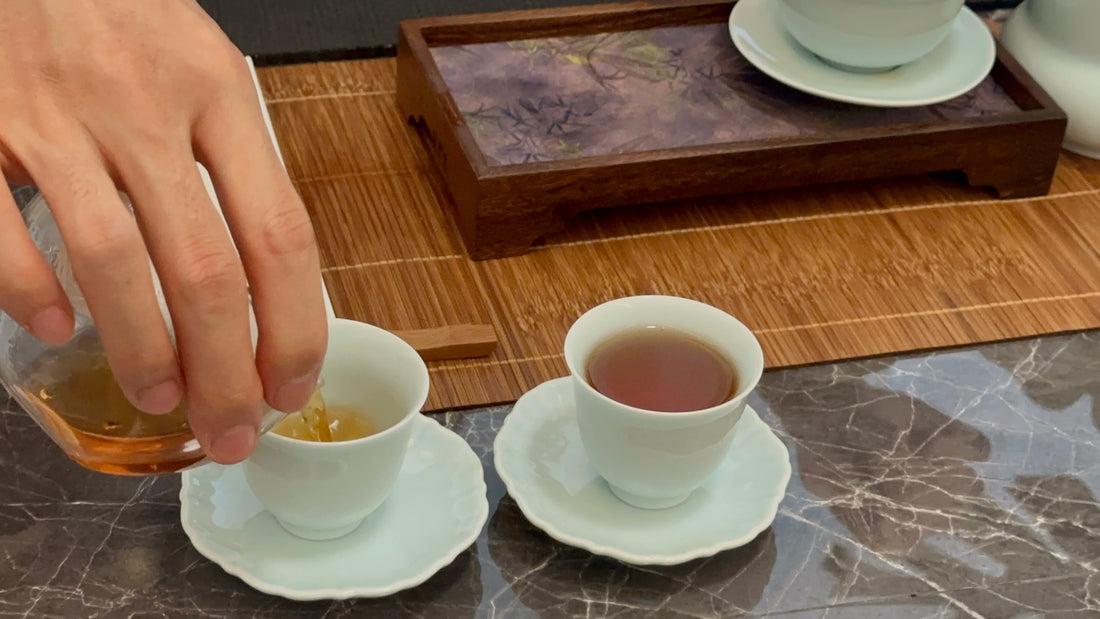 Pouring ripe Pu'er tea into small tea cups from a fair cup during Kung Fu tea session. Perfect for sharing and enjoying the rich flavors of Pu'er tea. 